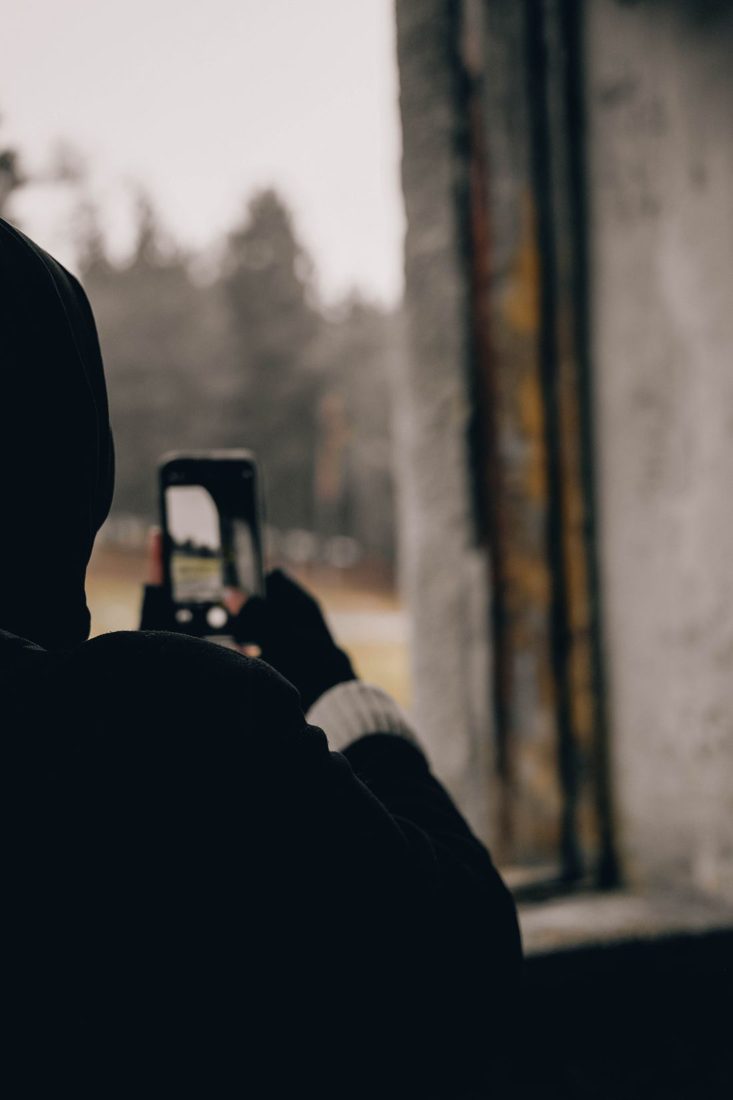 A person photographing a view through a window with a phone.