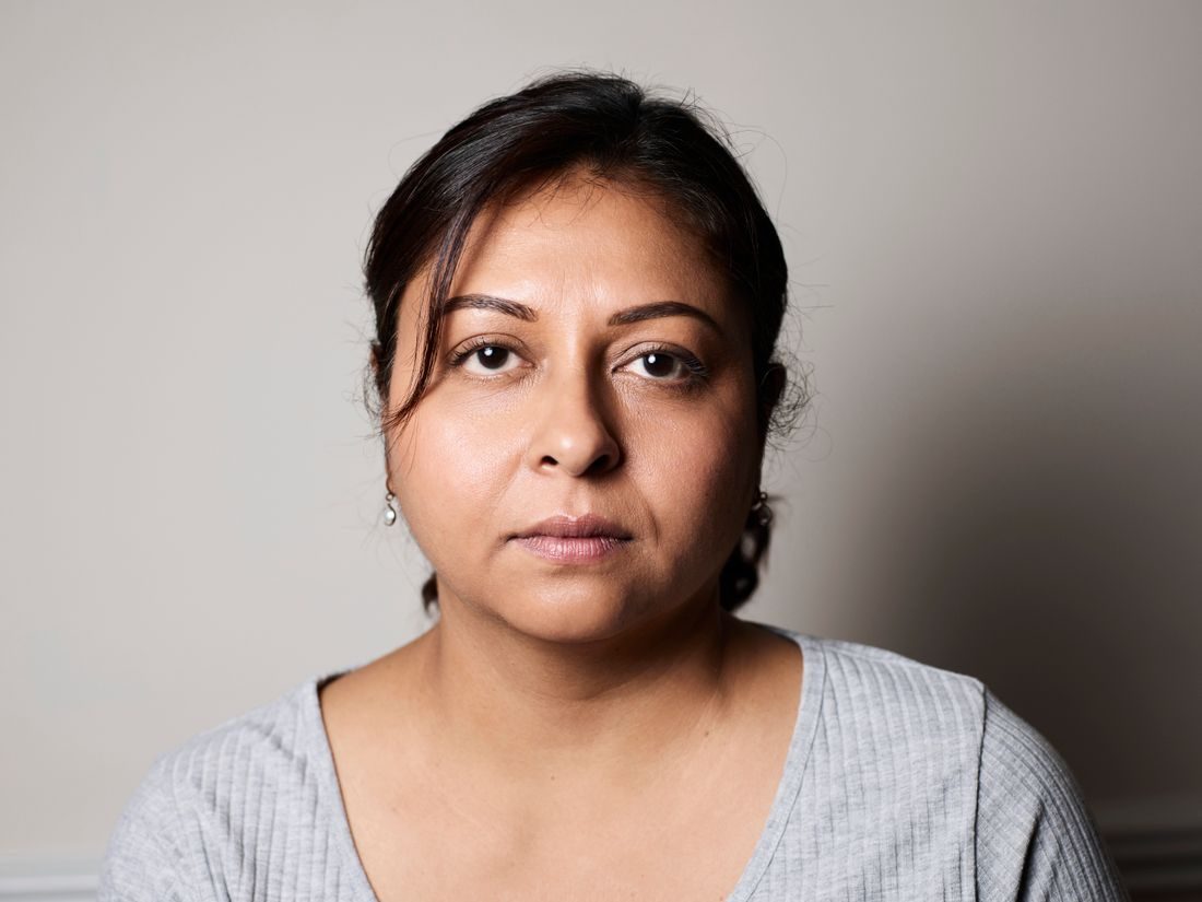 A woman facing the camera against a plain pale background.