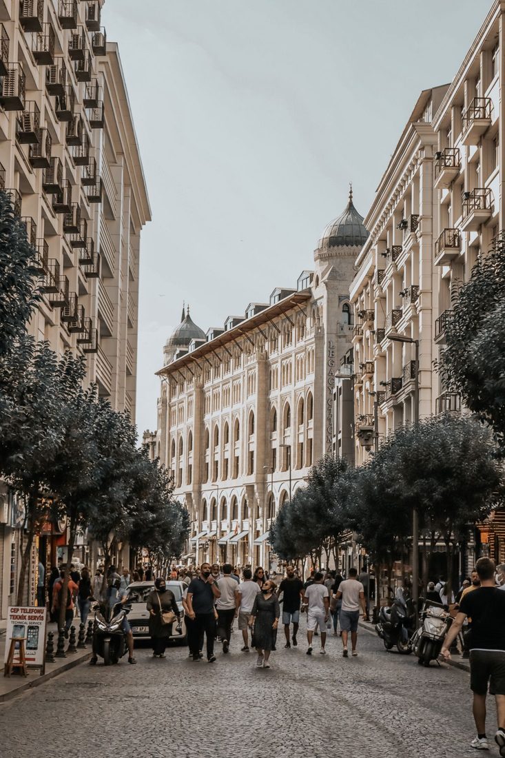 Pedestrians walking between tall buildings on a city street.