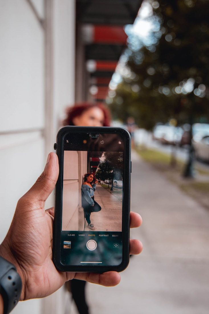 A hand holding a phone while photographing a person.