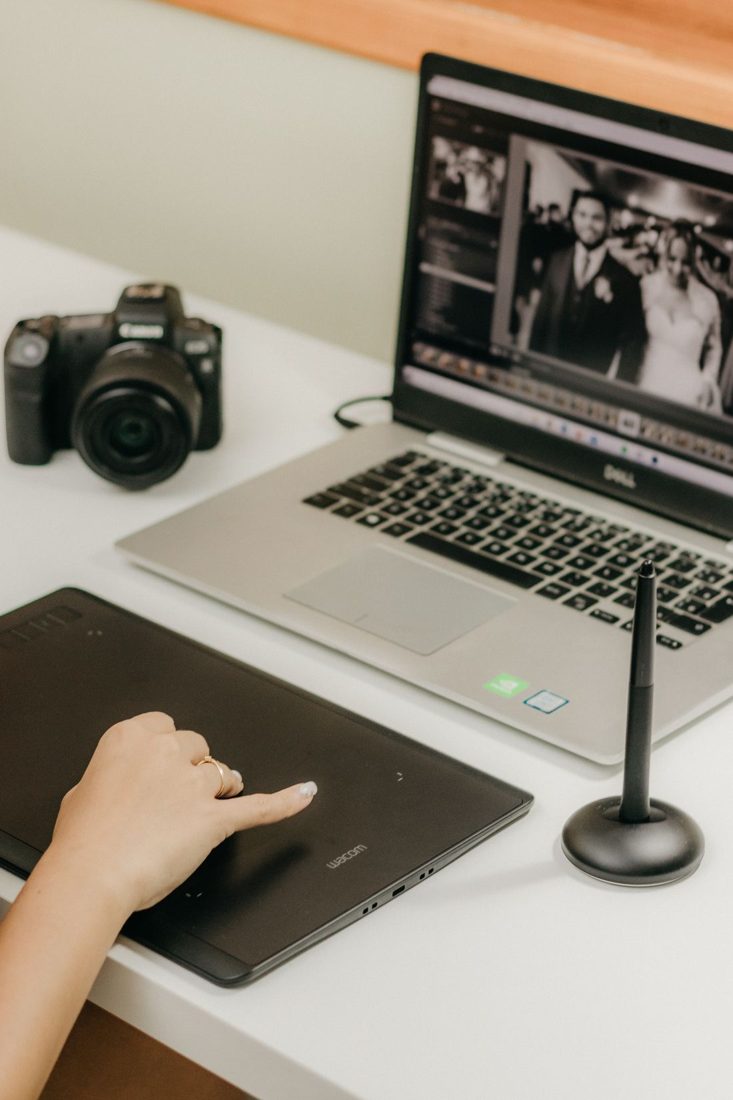 A laptop, camera and graphics tablet on a photo editing desk.