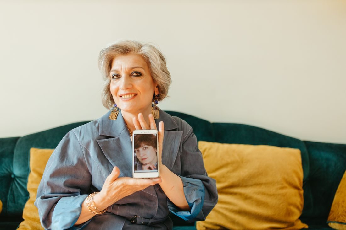 A woman holding a phone that displays an old portrait.