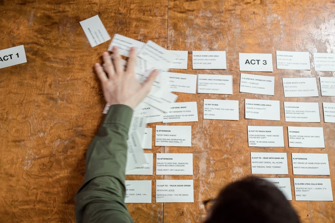 Hands arranging story cards on a wooden planning board.
