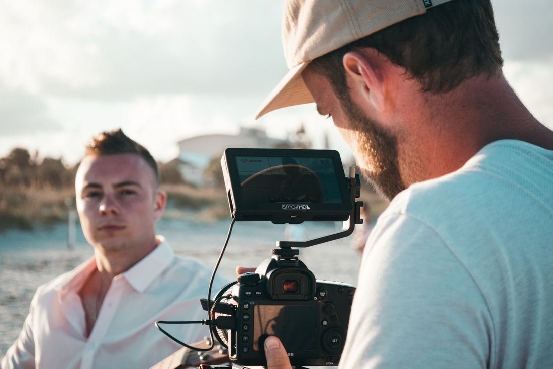 A camera operator framing a man during an outdoor shoot.