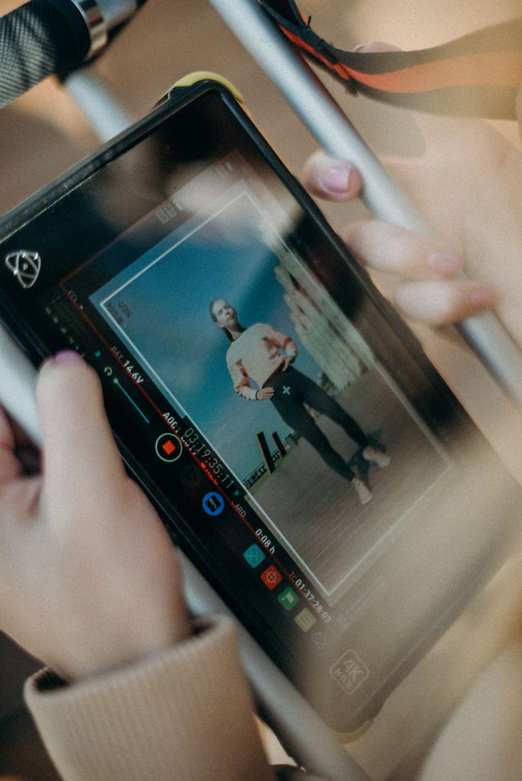 Hands holding a field monitor showing two people in a video.