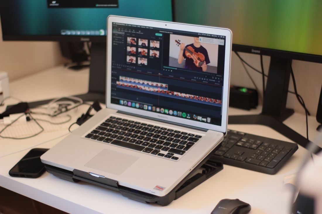 A laptop displaying a video preview and multitrack timeline.