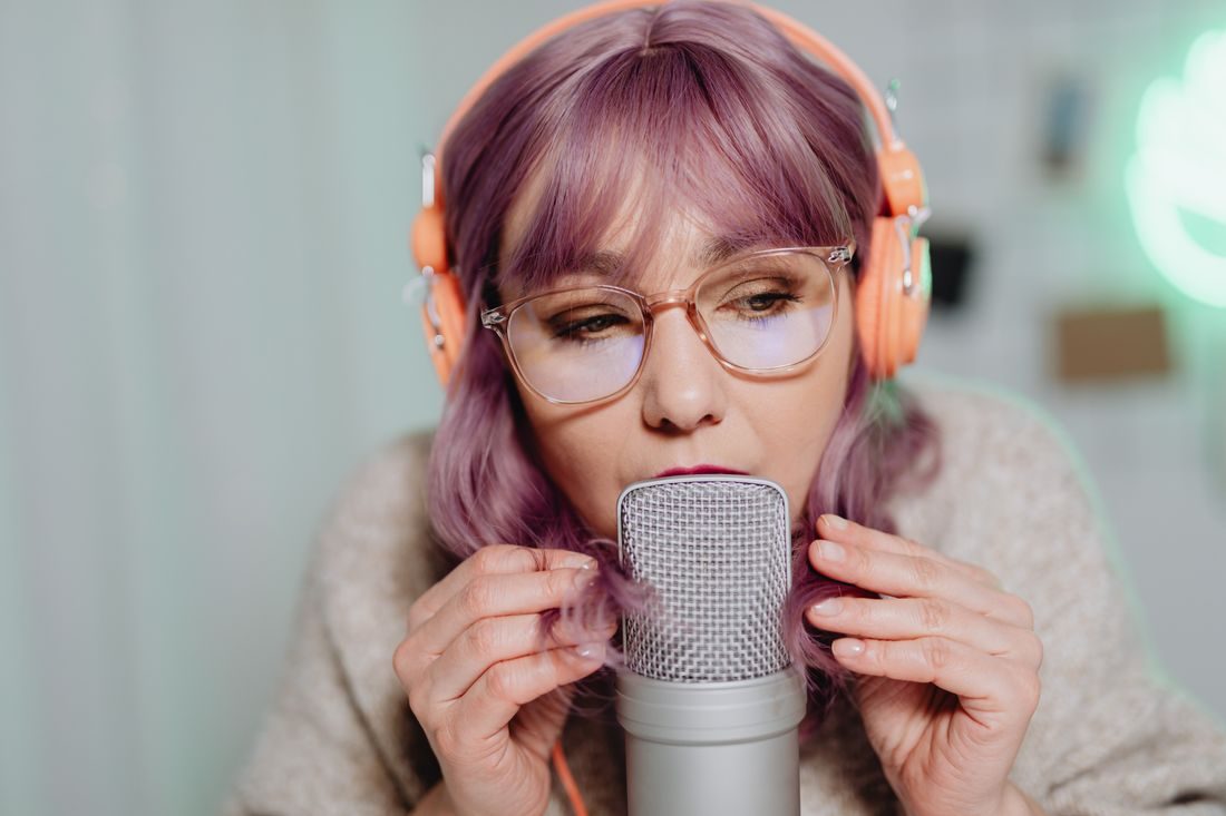 A woman speaking close to a microphone while wearing headphones.
