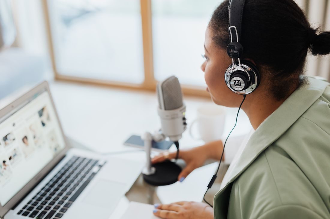 A woman using headphones, a microphone and a laptop.