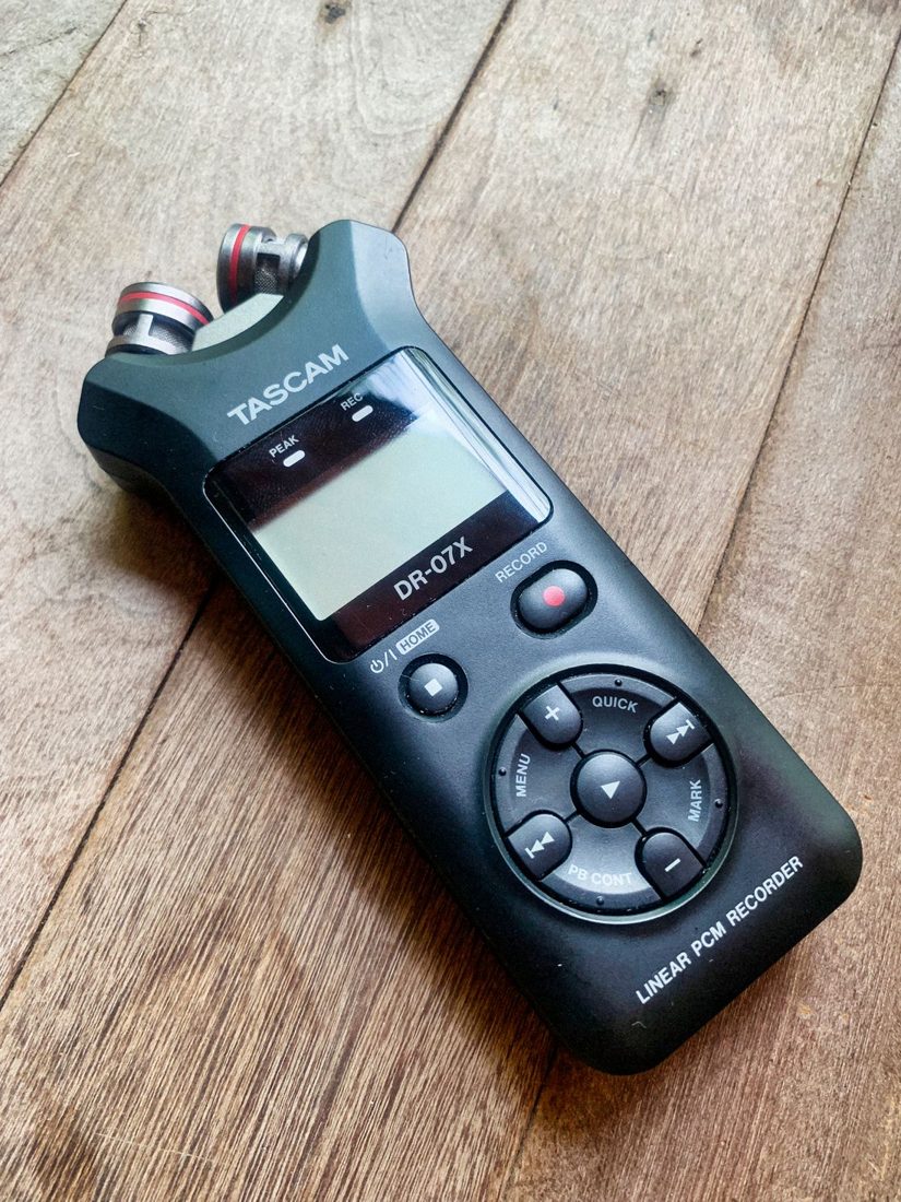 A portable Tascam audio recorder on a wooden surface.