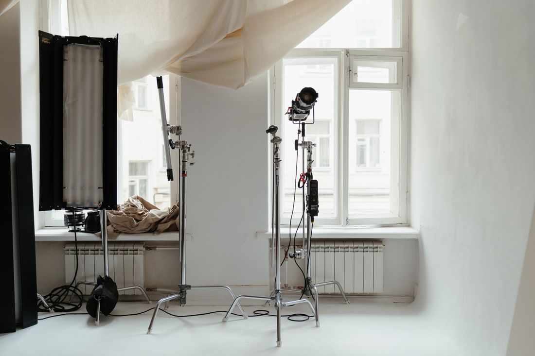Cameras and lighting equipment in a room with large windows.