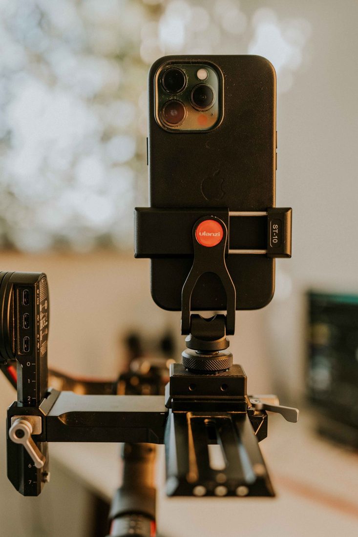 A phone held in a clamp above a tripod.