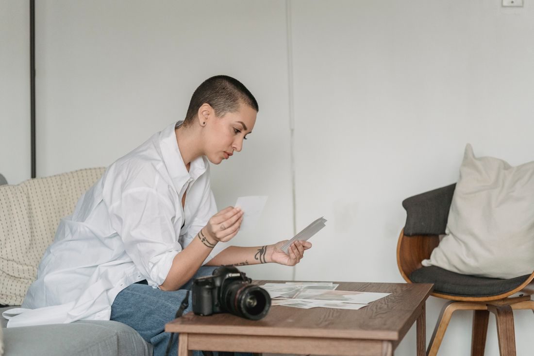 A person comparing printed photographs beside a camera.