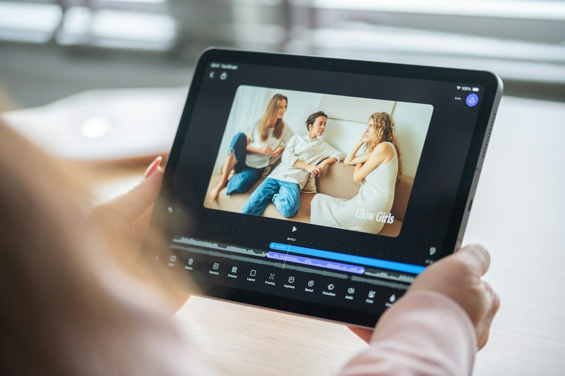 Hands holding a tablet with a video preview and editing timeline.