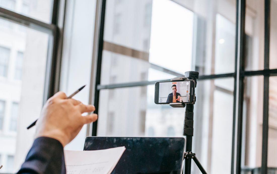 A phone on a tripod recording a person teaching indoors.