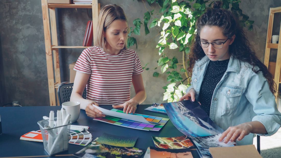 Two people reviewing printed designs and colour samples.
