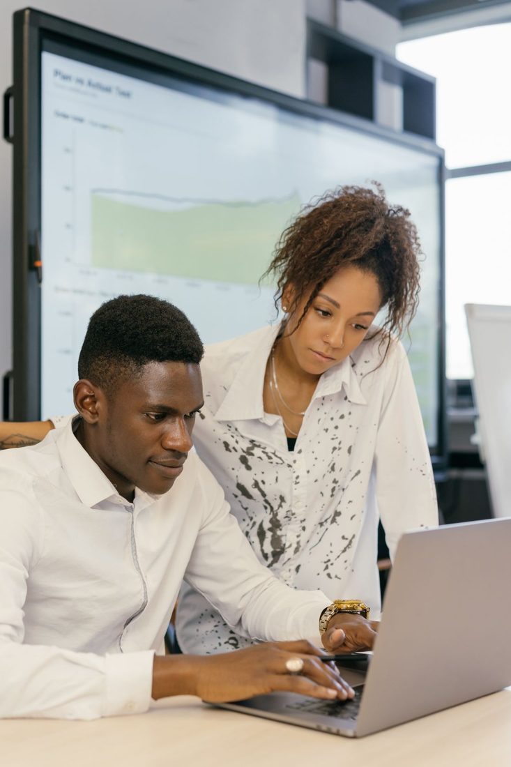 Two colleagues looking at a laptop together.