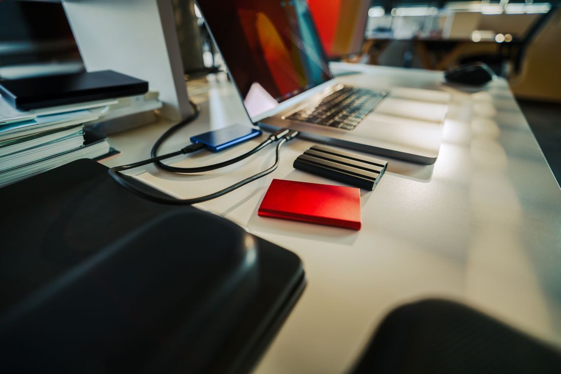 Several external drives connected beside a laptop on a desk.